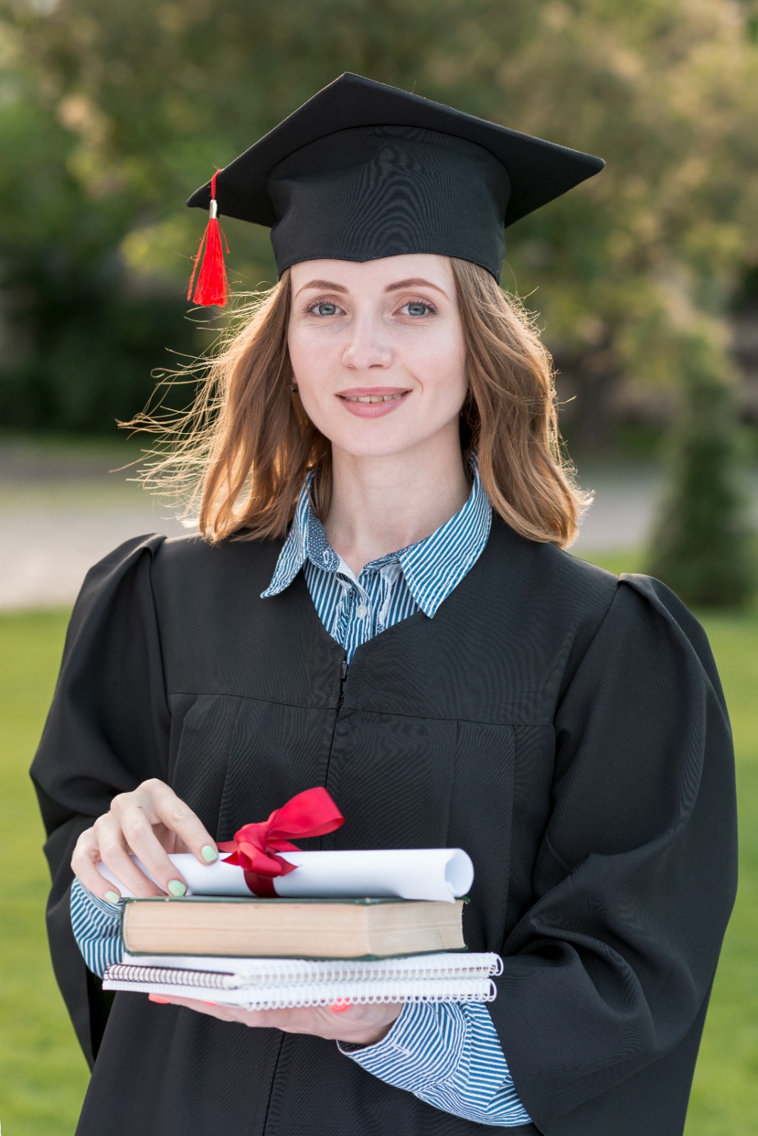 A young woman with a smile on her face holding her book and certificate after successfully finishing graduation convocation day.