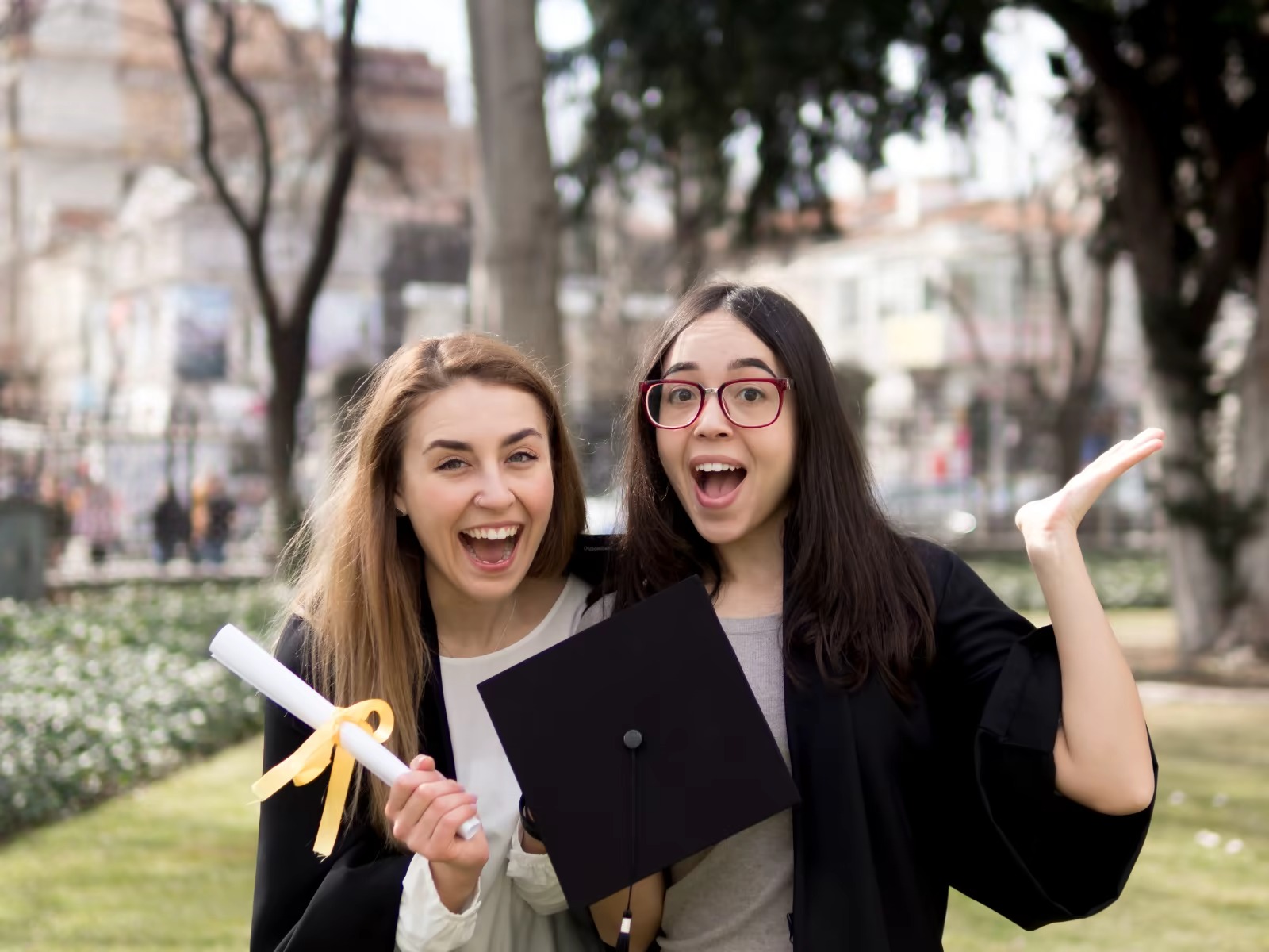 Two young ladies proudly carry their diplomas as they celebrate their graduation